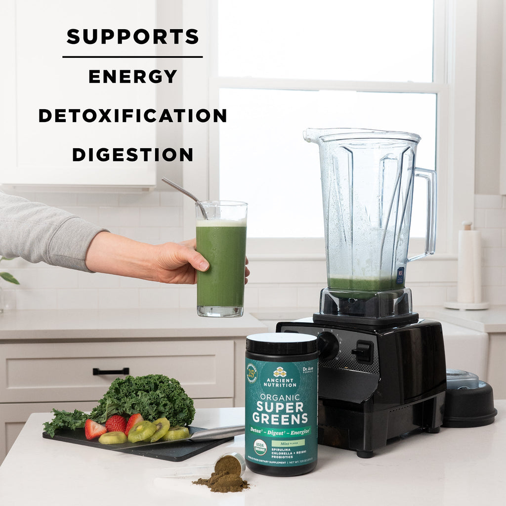 a bottle of Organic SuperGreens Powder Mint Flavor next to a blender