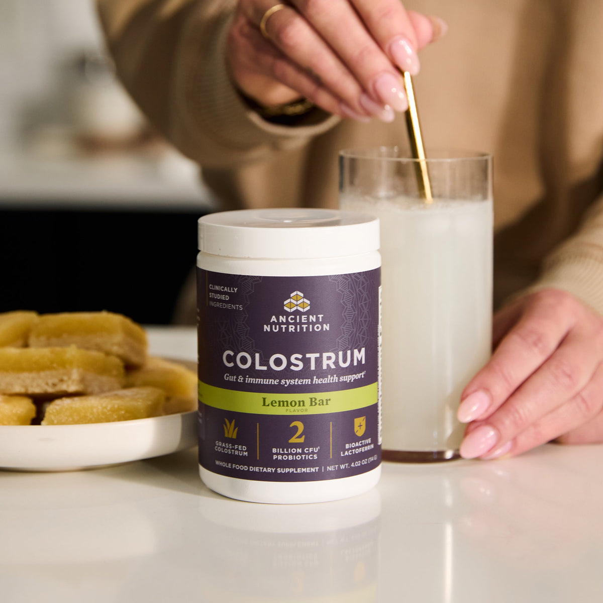 a bottle of Colostrum Powder Lemon Bar Flavor (60 Servings) getting mixed in water