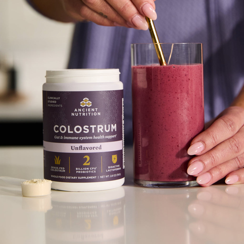 a bottle of Colostrum Powder Unflavored (60 Servings) next to a smoothie