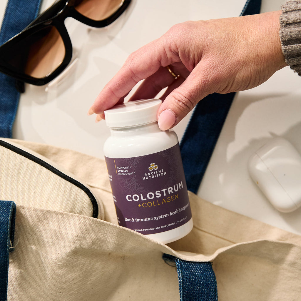 a person holding a bottle of Colostrum + Collagen Capsules (25 Servings) 