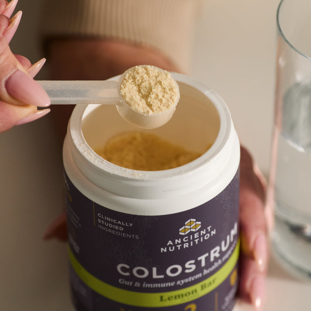 a scoop of Colostrum Powder Lemon Bar Flavor (60 Servings) 
