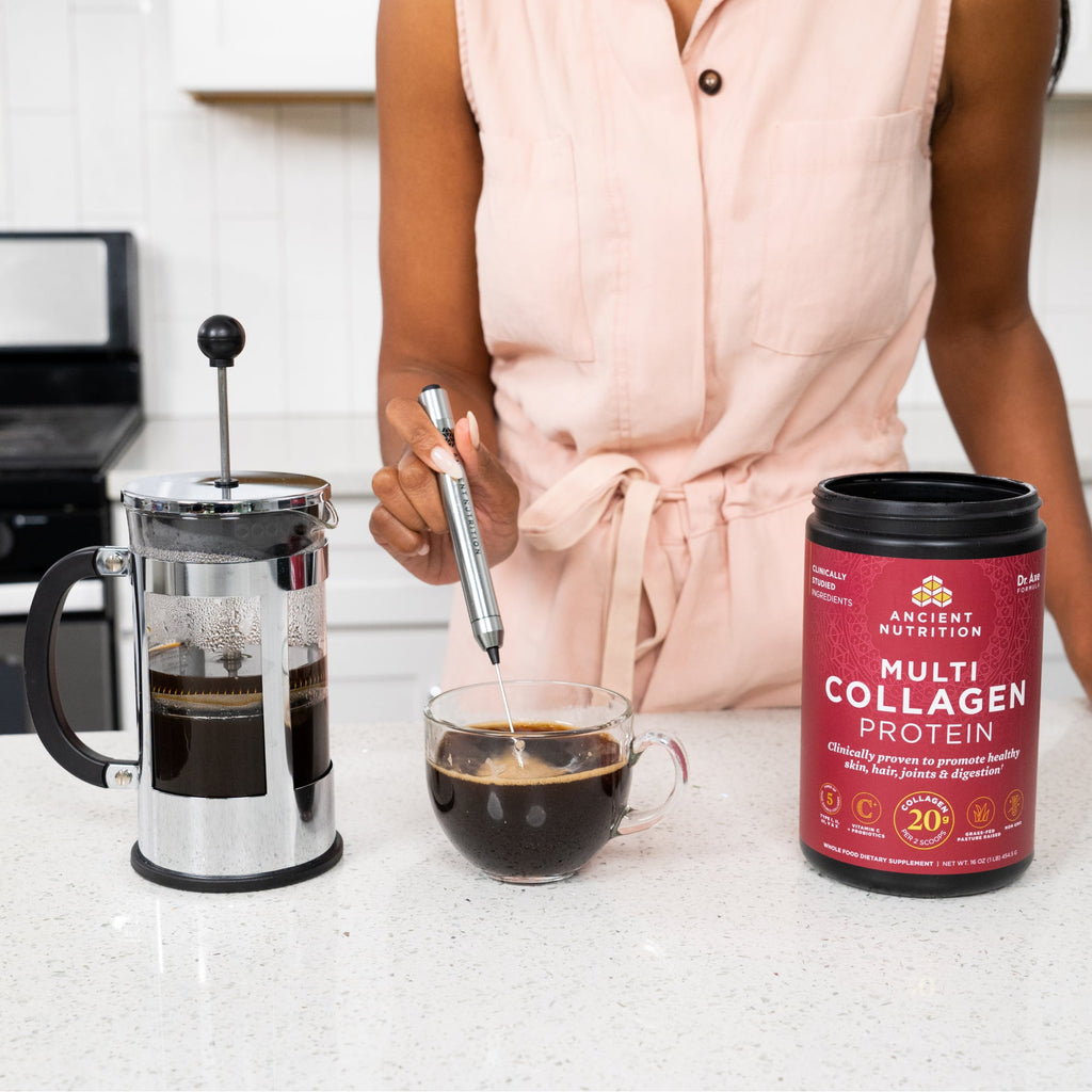 woman using a frother to stir coffee