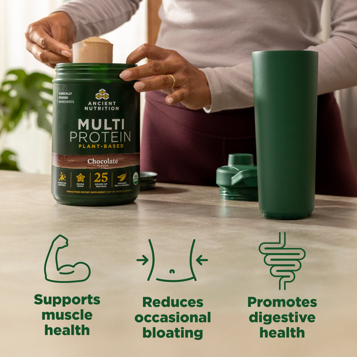 Person opening a container of Ancient Nutrition Multi Protein, with a green tumbler on a table.