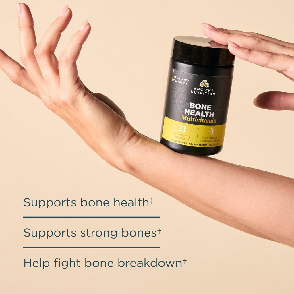 Multivitamin supplement for bone health held by a hand on a beige background