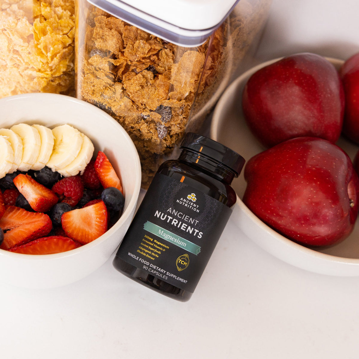 a bottle of Ancient Nutrients Magnesium Capsules (30 Servings) next to fruit bowls