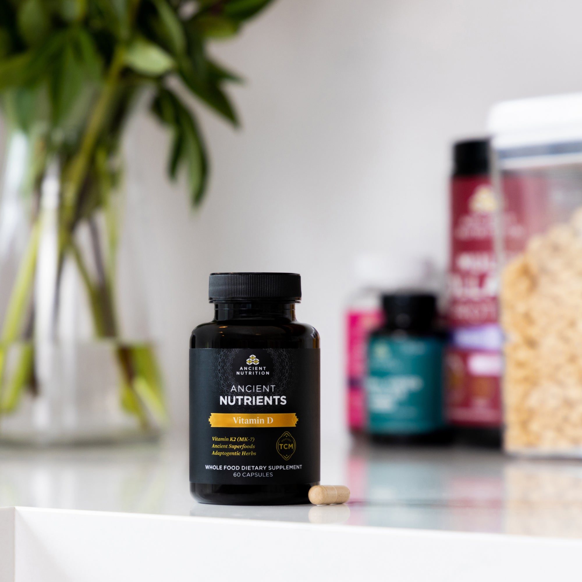 Ancient Nutrients Vitamin D3 + K2 Capsules bottle on a counter with other supplements in the background