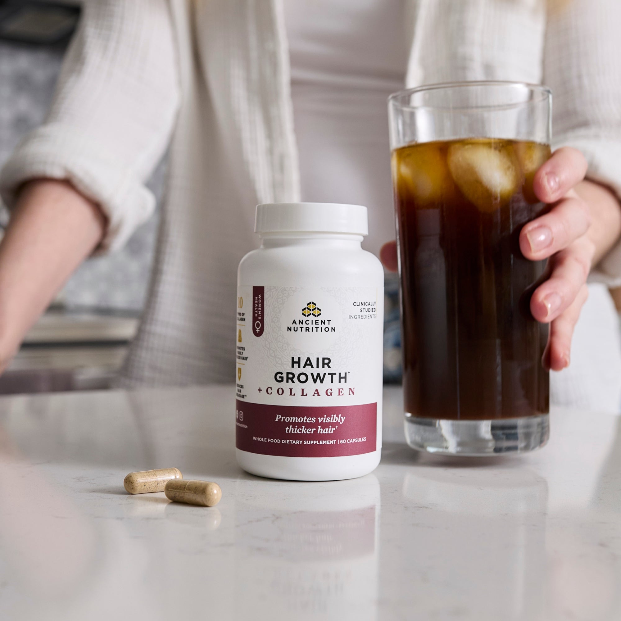 a bottle of Hair Growth + Collagen Capsules next to an iced coffee