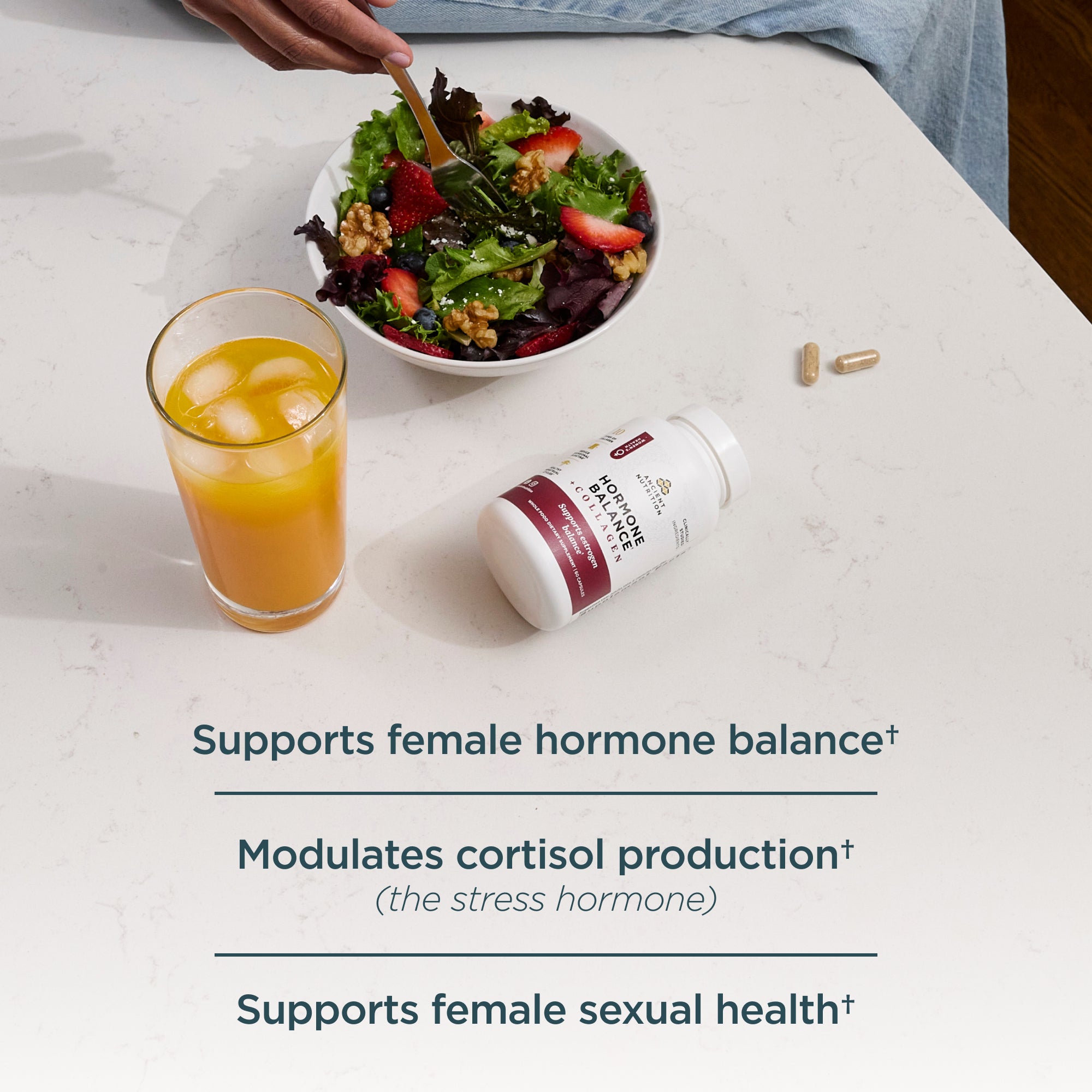 a bottle of Hormone Balance + Collagen Capsules next to a salad and turmeric drink