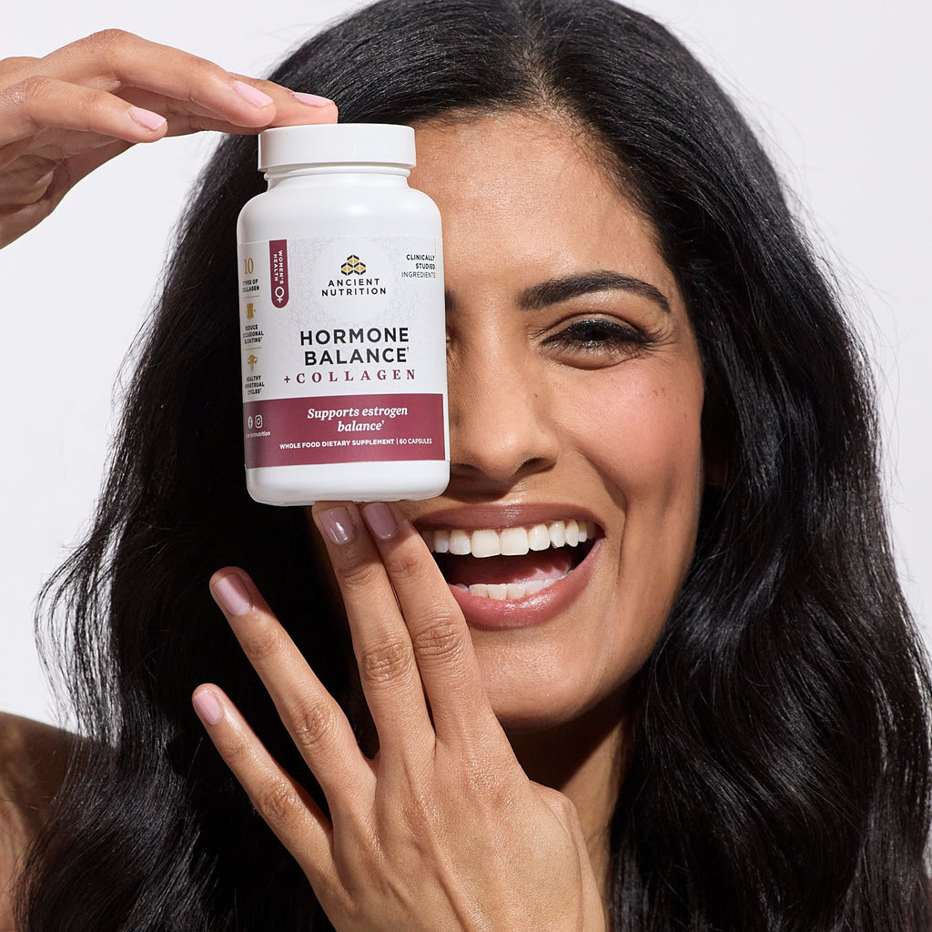 a woman holding a bottle of Hormone Balance + Collagen Capsules 