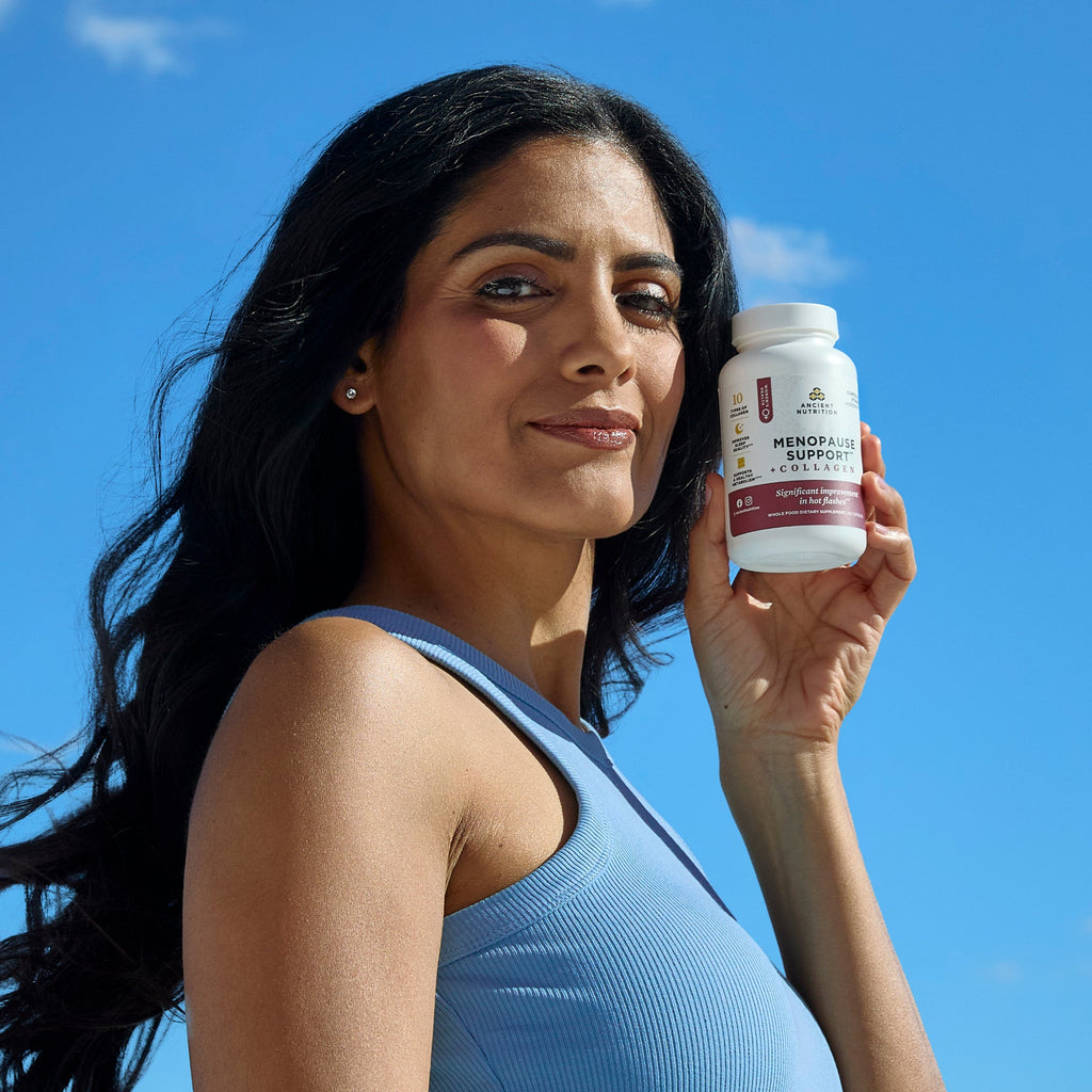 a woman holding a bottle of Menopause Support + Collagen Capsules