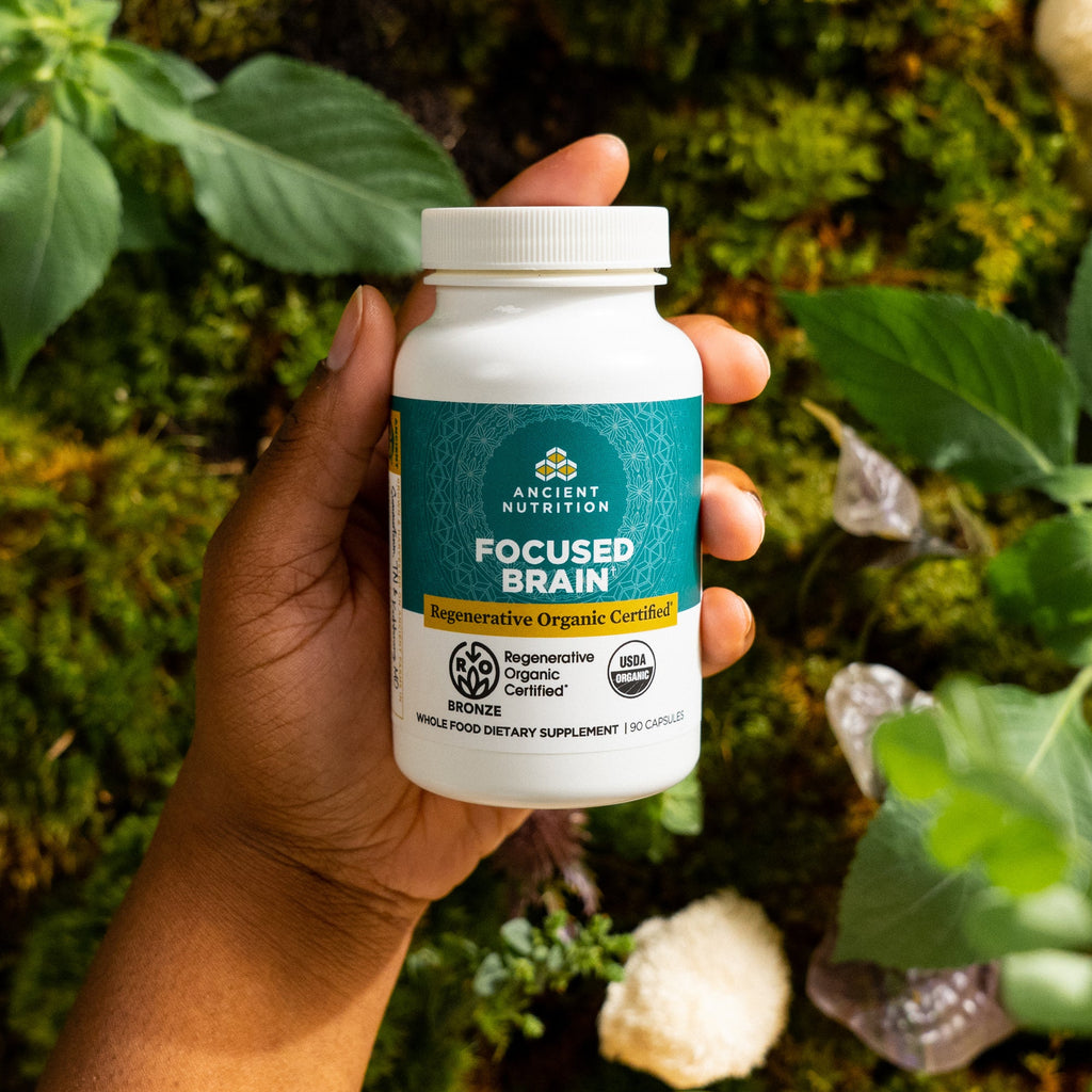 a person holding a bottle of Regenerative Organic Certified™ Focused Brain
