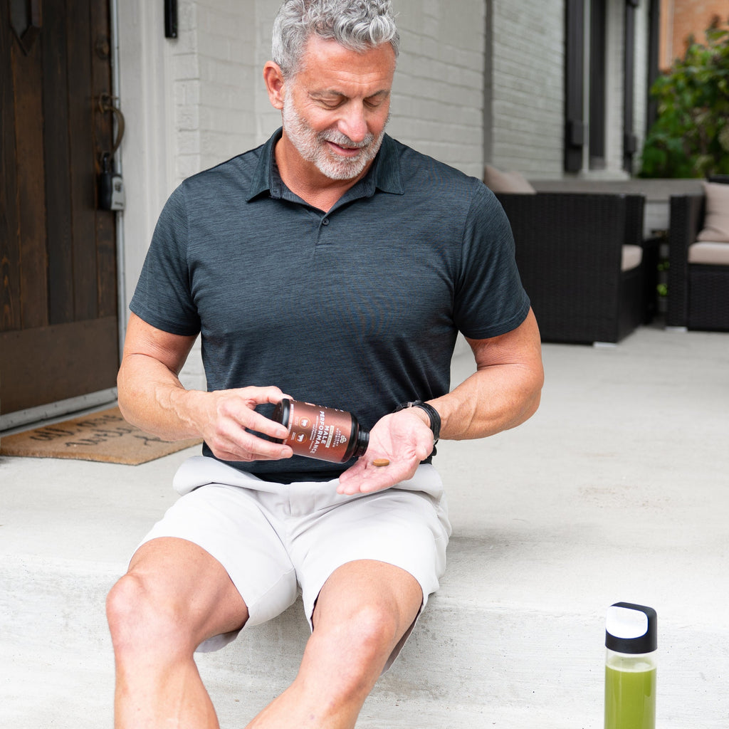 a man holding a bottle of Male Performance Once Daily Tablets