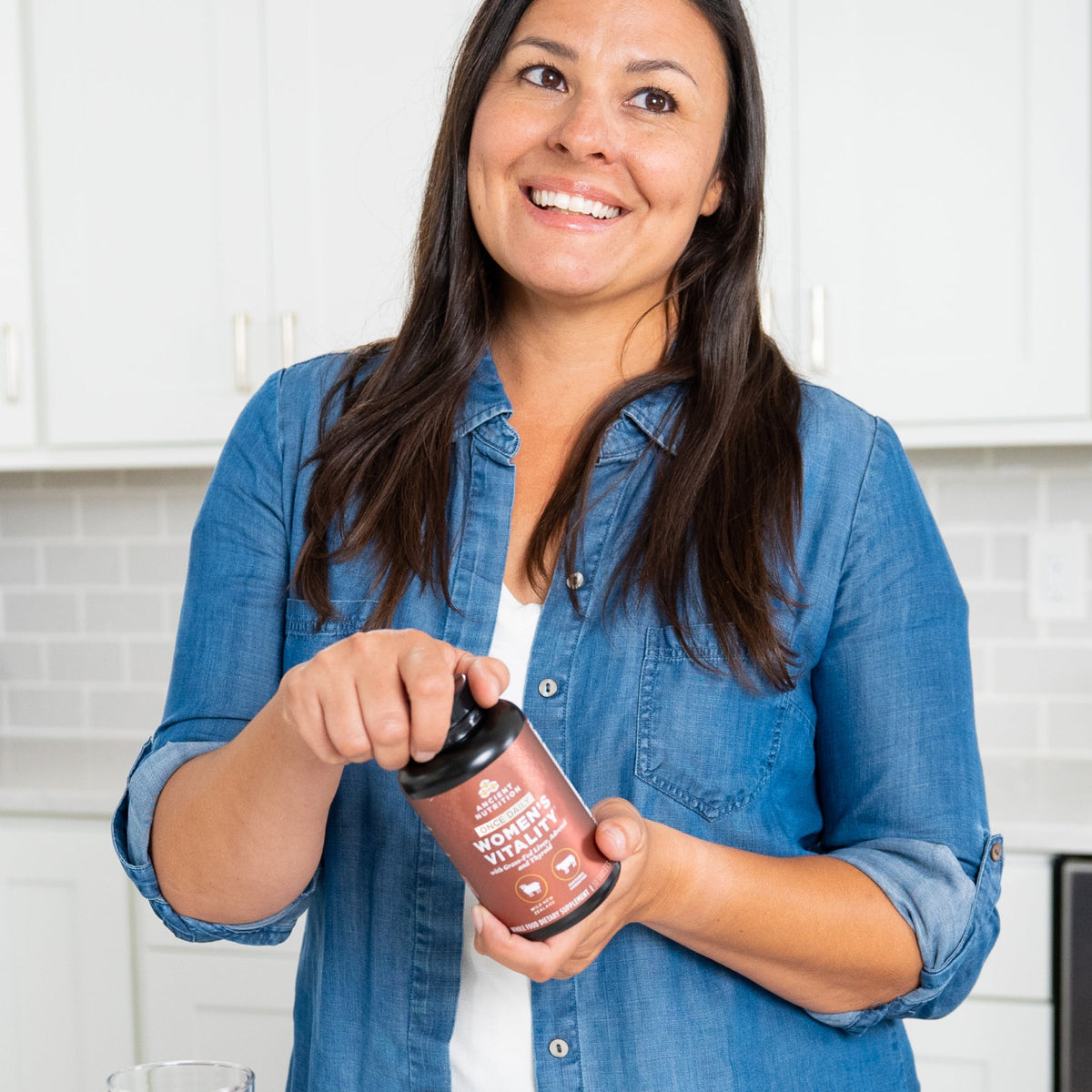 a woman holding a bottle of Women's Vitality Once Daily Tablets