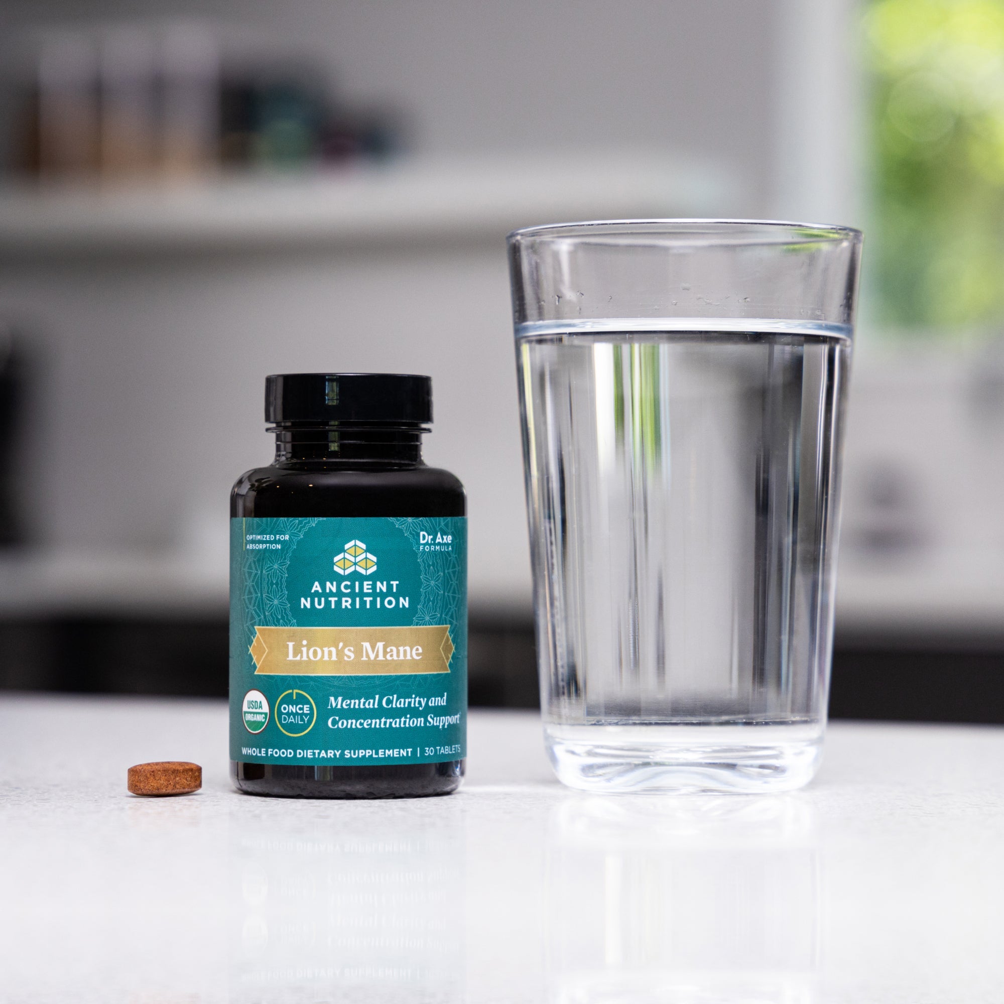 a bottle of Lion's Mane Mental Clarity and Concentration Tablets next to a glass of water