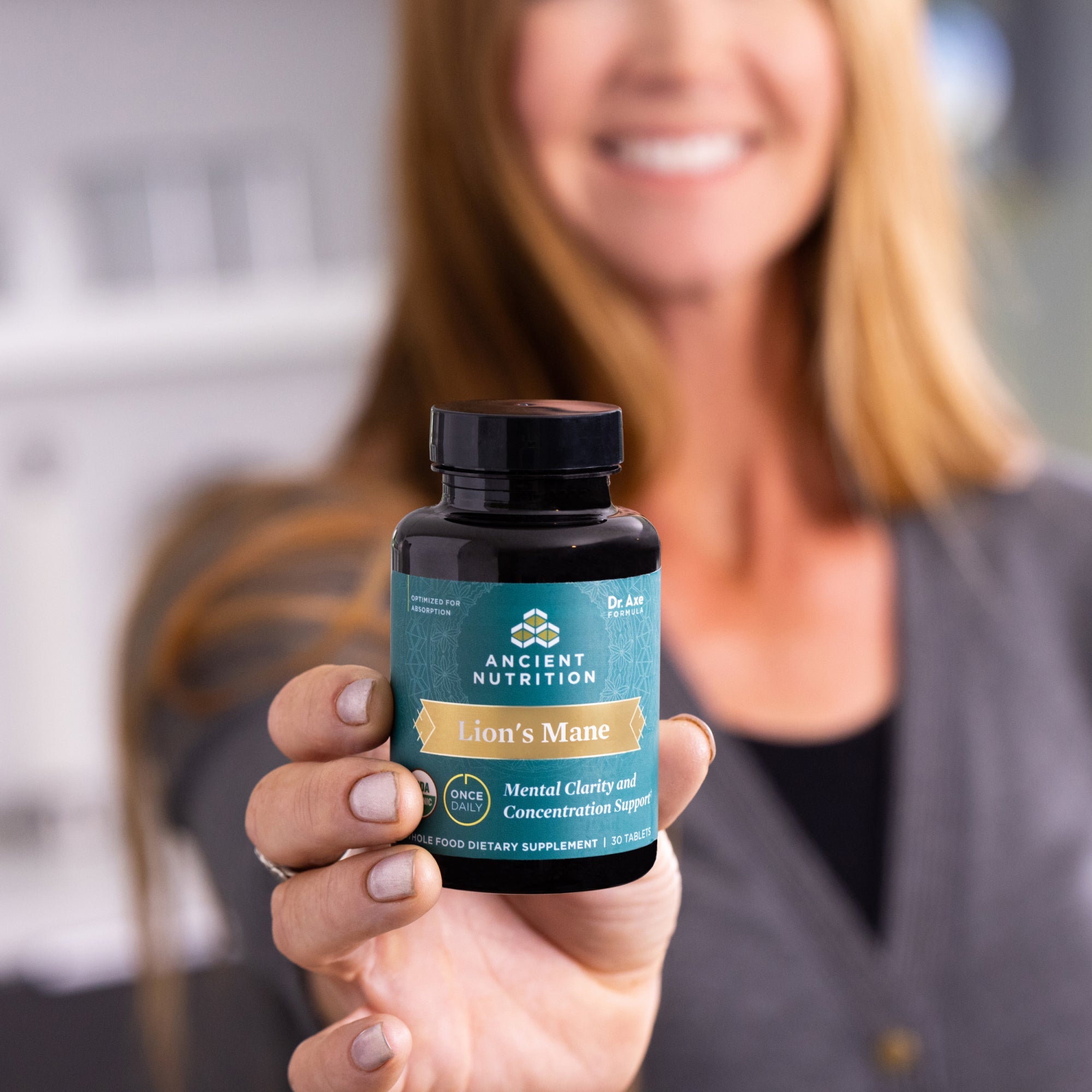 a woman holding a bottle of Lion's Mane Mental Clarity and Concentration Tablets on a counter