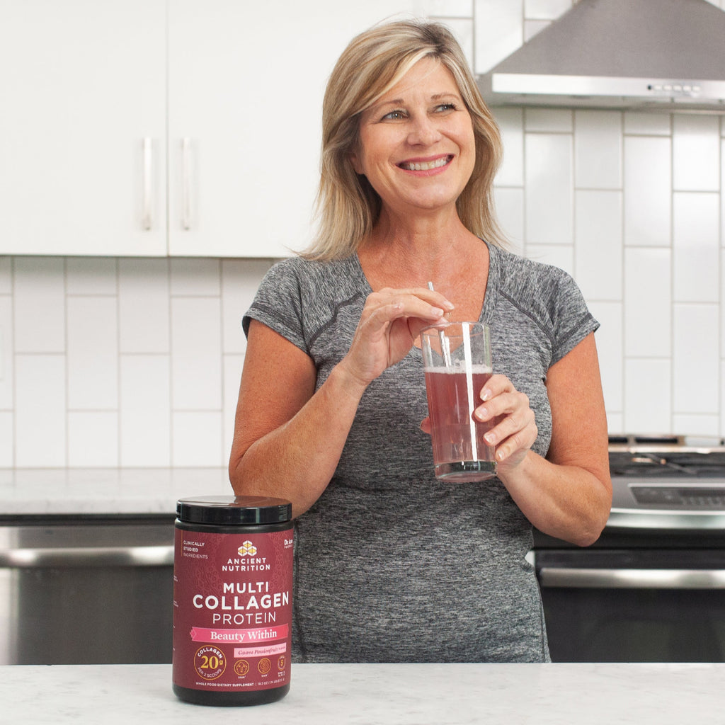 woman in a kitchen drinking Multi Collagen Protein Beauty Within Powder