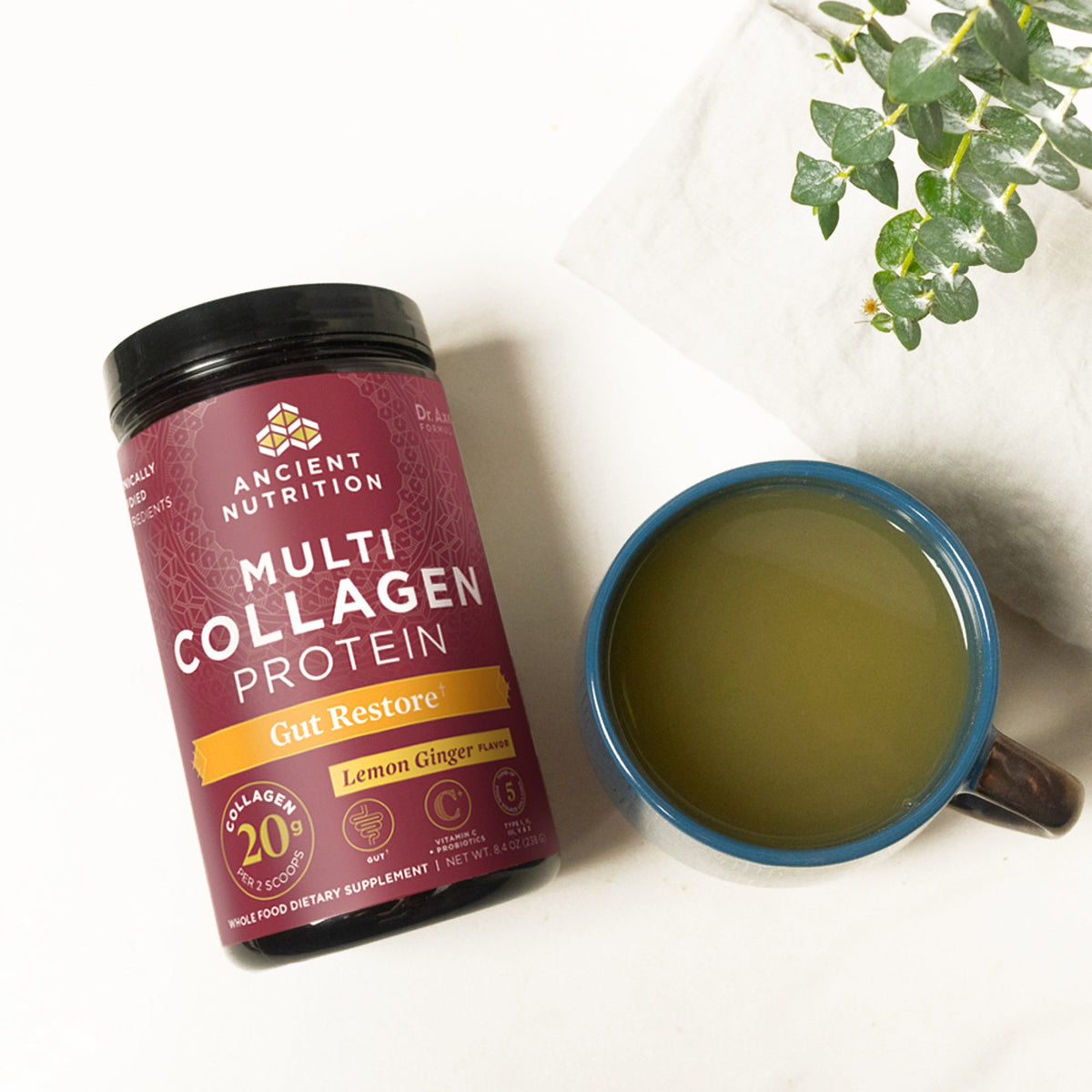 Multi Collagen Protein Gut Restore Powder Lemon Ginger bottle next to a mug