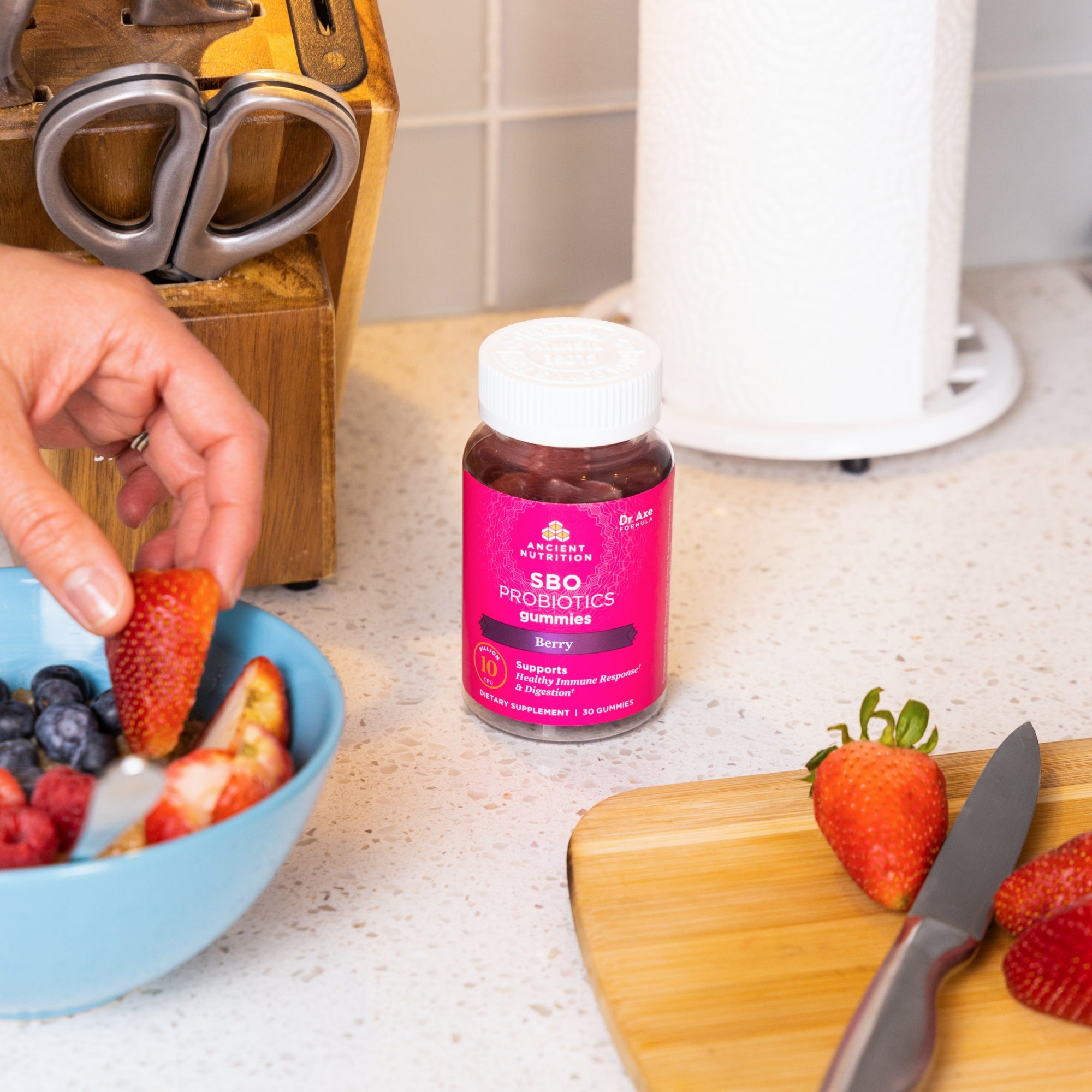 a bottle of SBO Probiotics Gummies Berry next to fruit