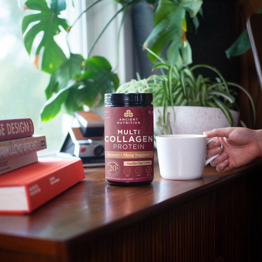 a bottle of Multi Collagen Protein Beauty + Sleep Support Powder on a desk with books and plants