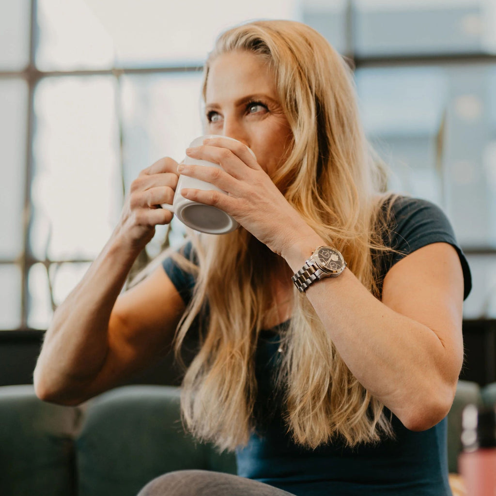 a woman drinking from a white coffee cup