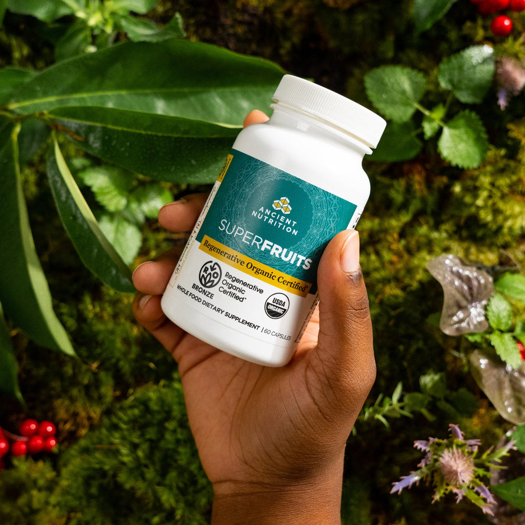a person holding a bottle of Regenerative Organic Certifiedª SuperFruits