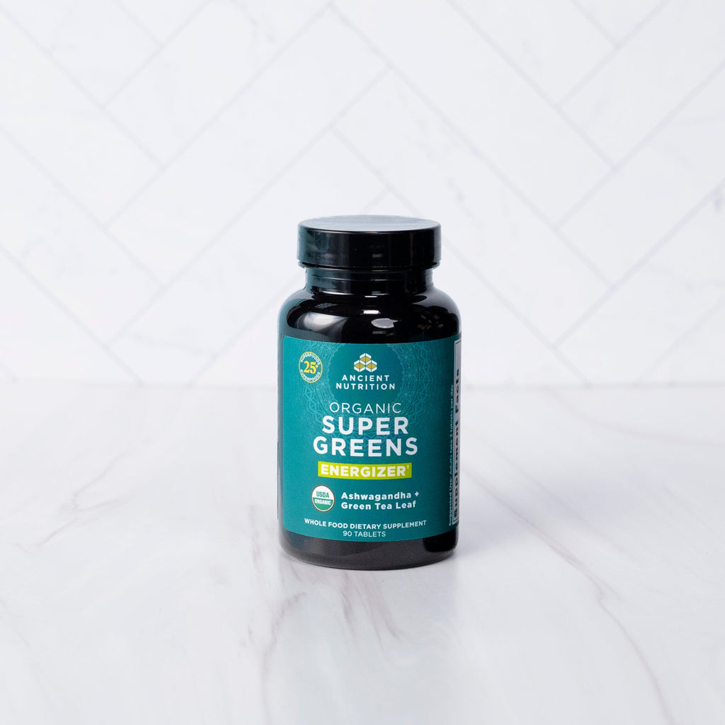 a bottle of Organic SuperGreens Energizer Tablets on a marble countertop