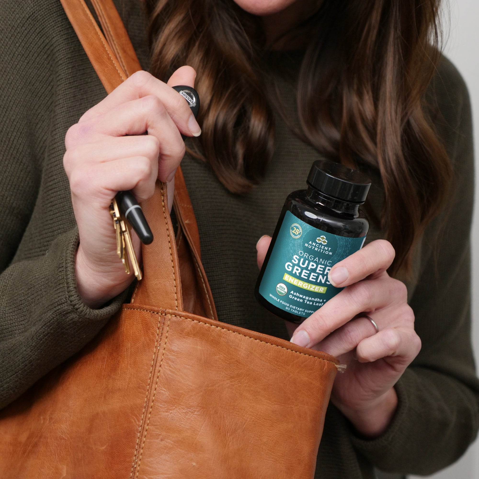 a woman taking an Organic Super Greens Energizer Tablet out of her purse