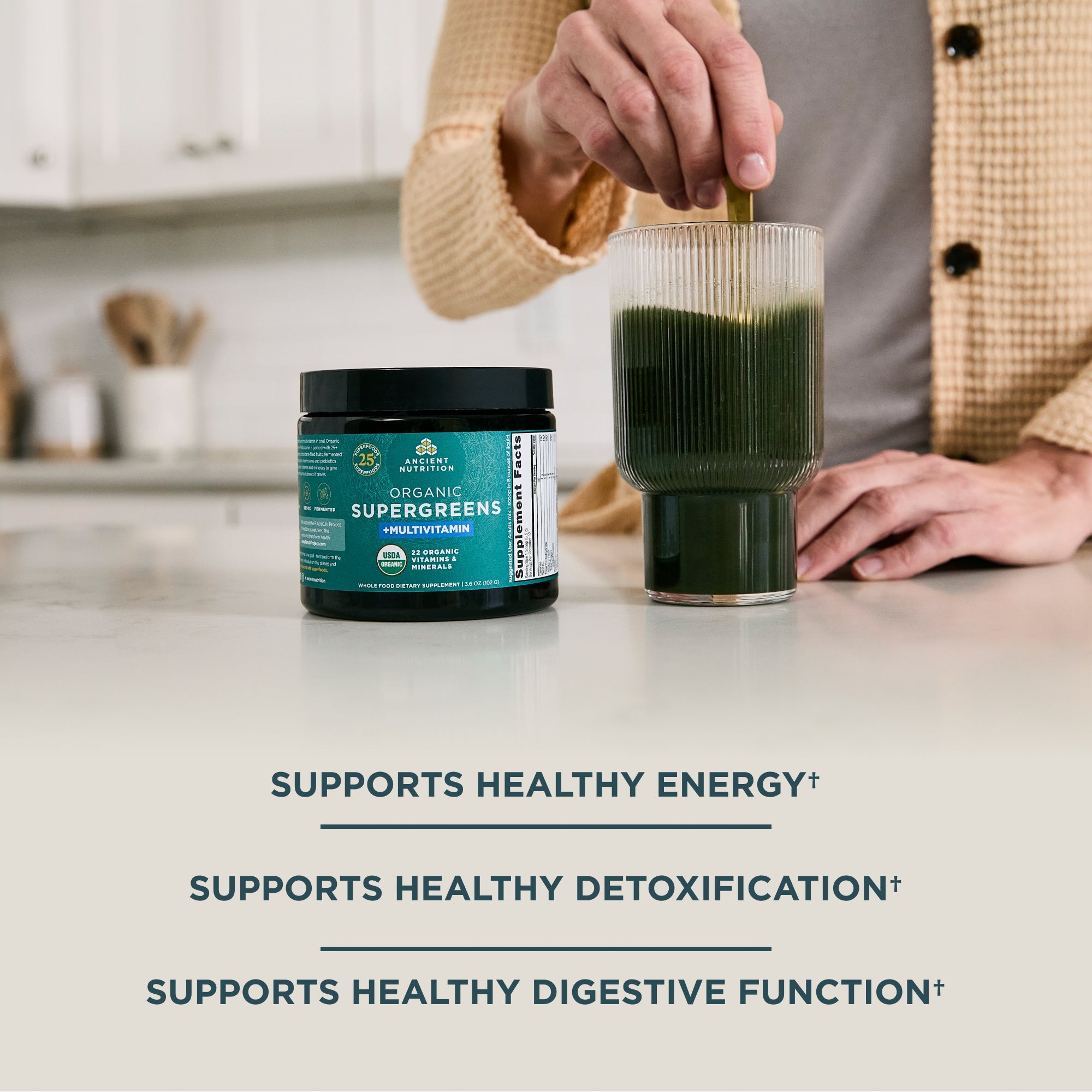 a person mixing Organic SuperGreens + Multivitamin Powder (12 Servings) in a glass of water