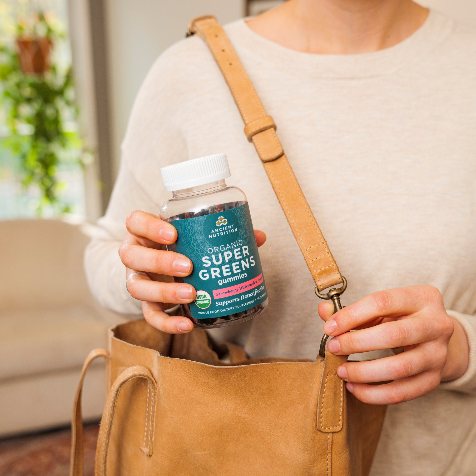 a woman taking Organic Super Greens Gummies Strawberry Watermelon Flavor our of her purse