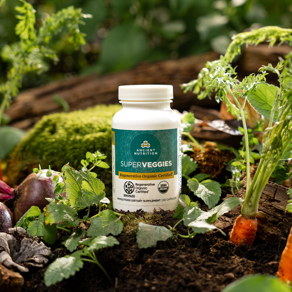 bottle of Regenerative Organic Certifiedª SuperVeggies in a vegetable garden