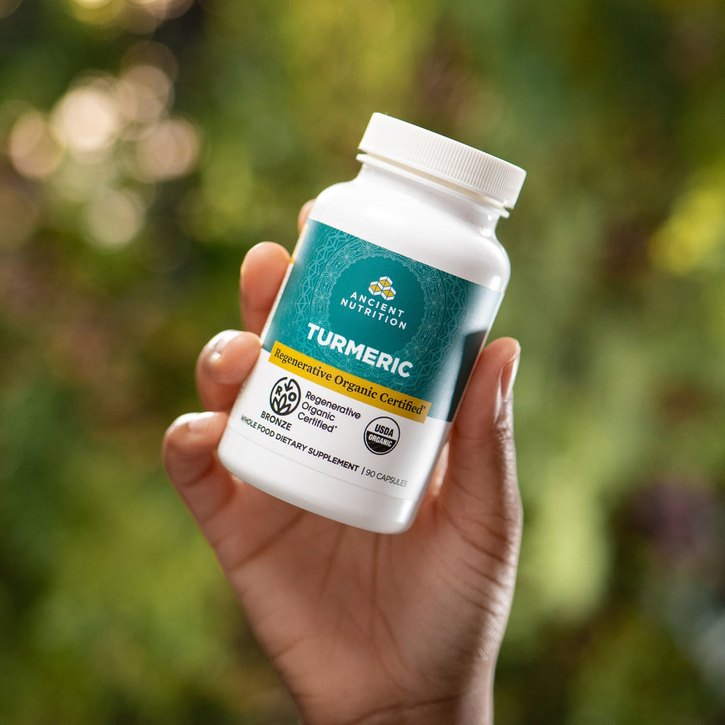 a person holding a bottle of Regenerative Organic Certified™ Turmeric