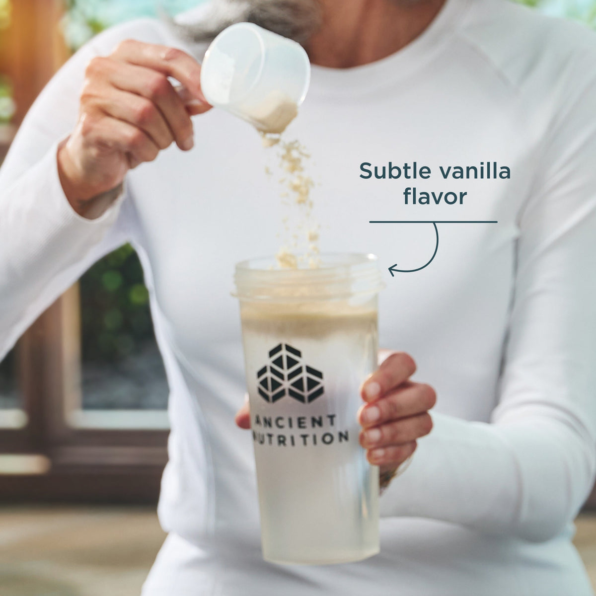 Person pouring a supplement into a Ancient Nutrition shaker bottle with text 'Subtle vanilla flavor'.