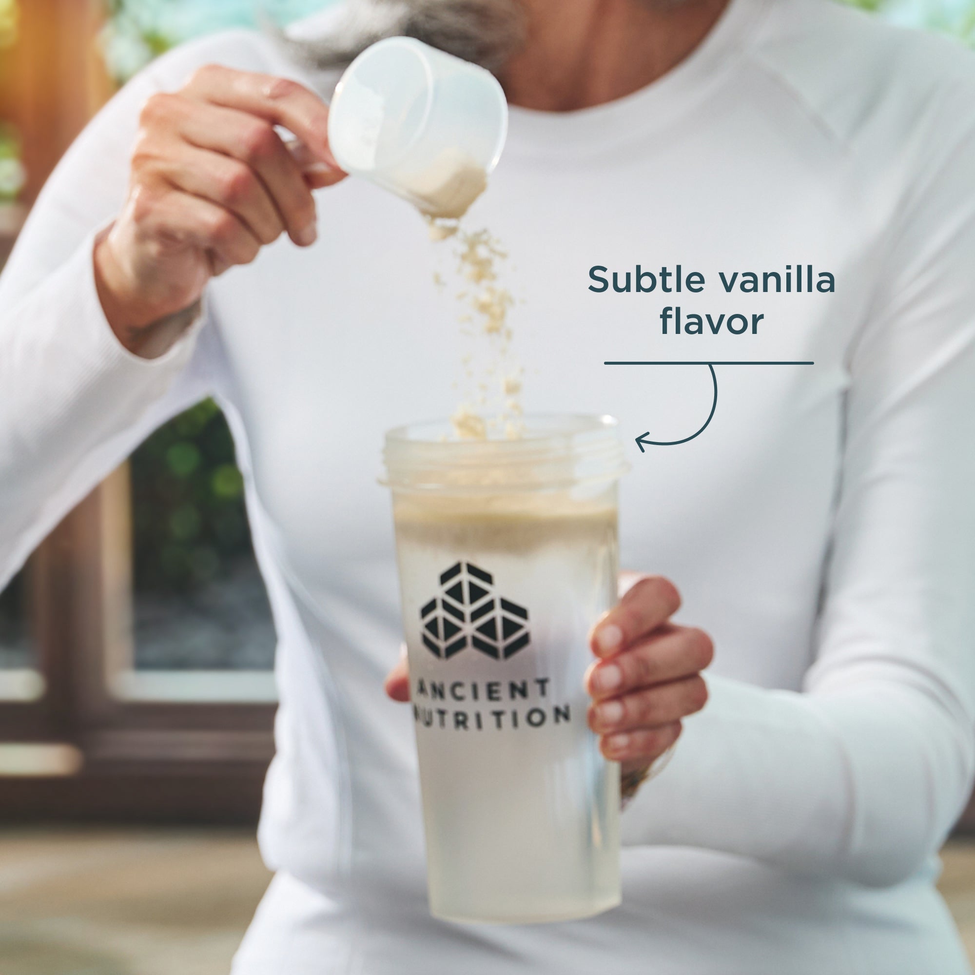 Person pouring a supplement into a Ancient Nutrition shaker bottle with text 'Subtle vanilla flavor'.