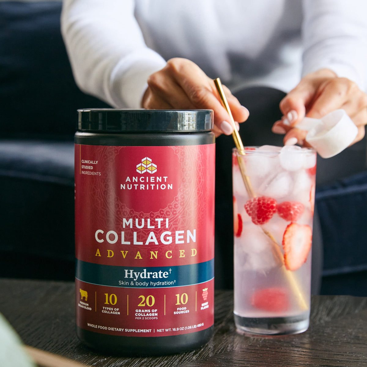 Multi Collagen Advanced Hydrate Powder Mixed Berry getting stirred into a glass of water